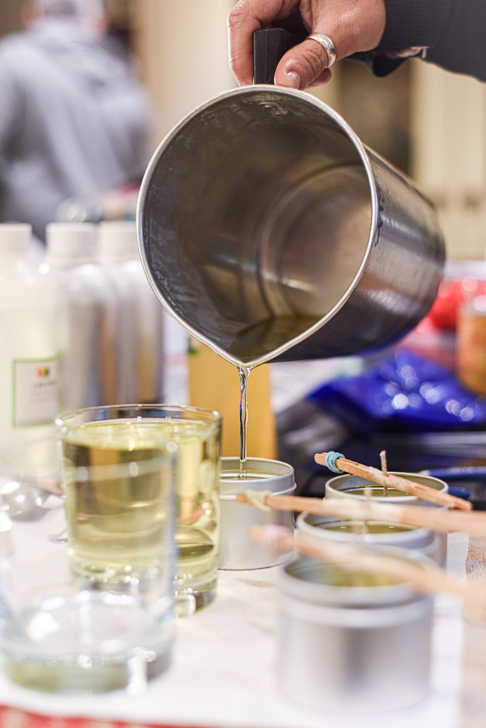 Creative occupation of candle making showing the pouring of liquid wax into jars